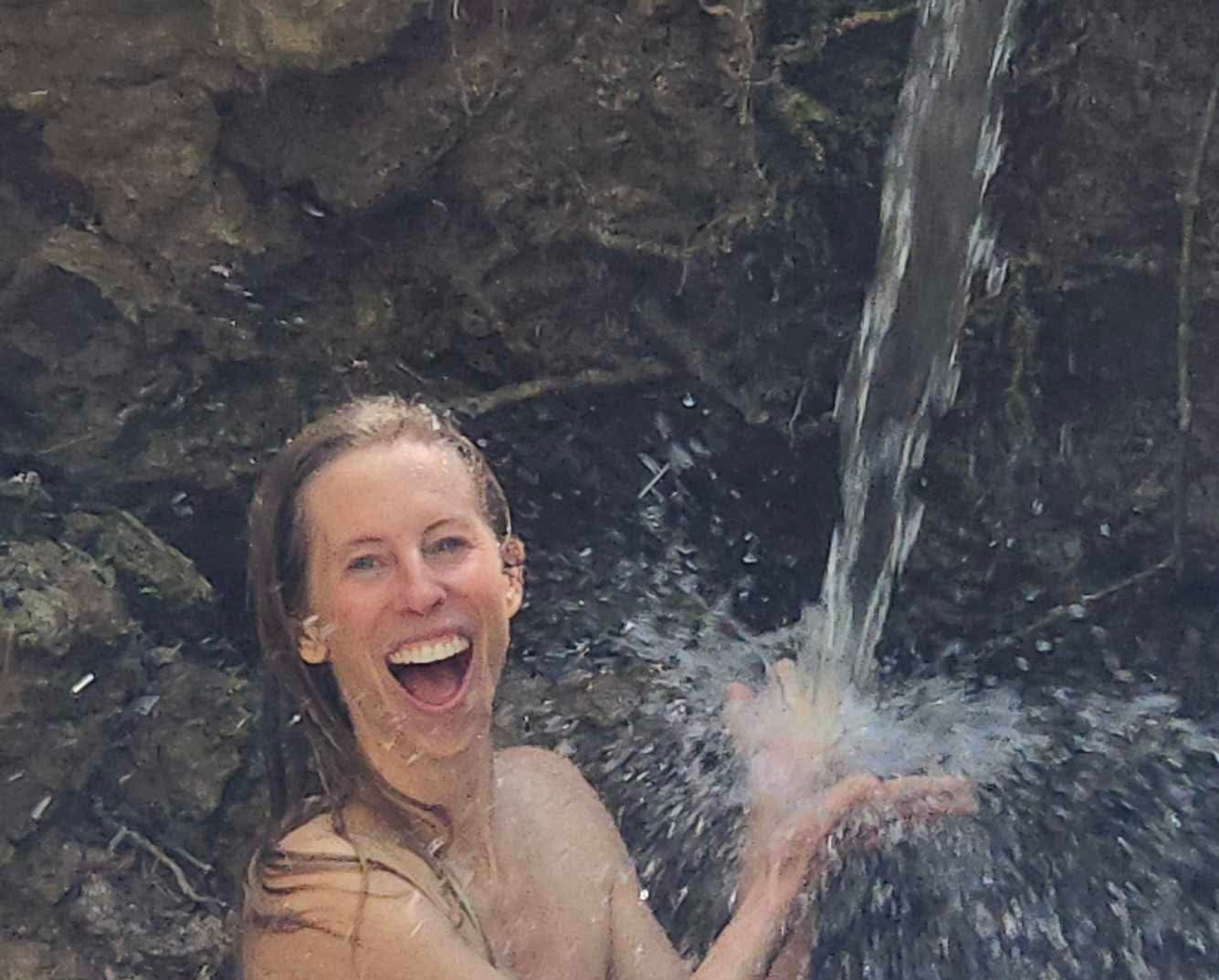 Kelci Heart laughing under a waterfall